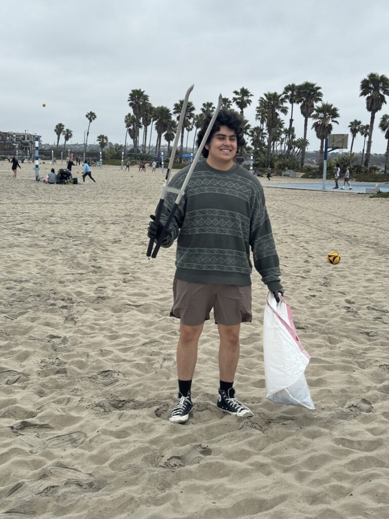 Student with grabber and trash bag on the beach — Black Tech Link BIPOC Coastal Research Program (BCRP)