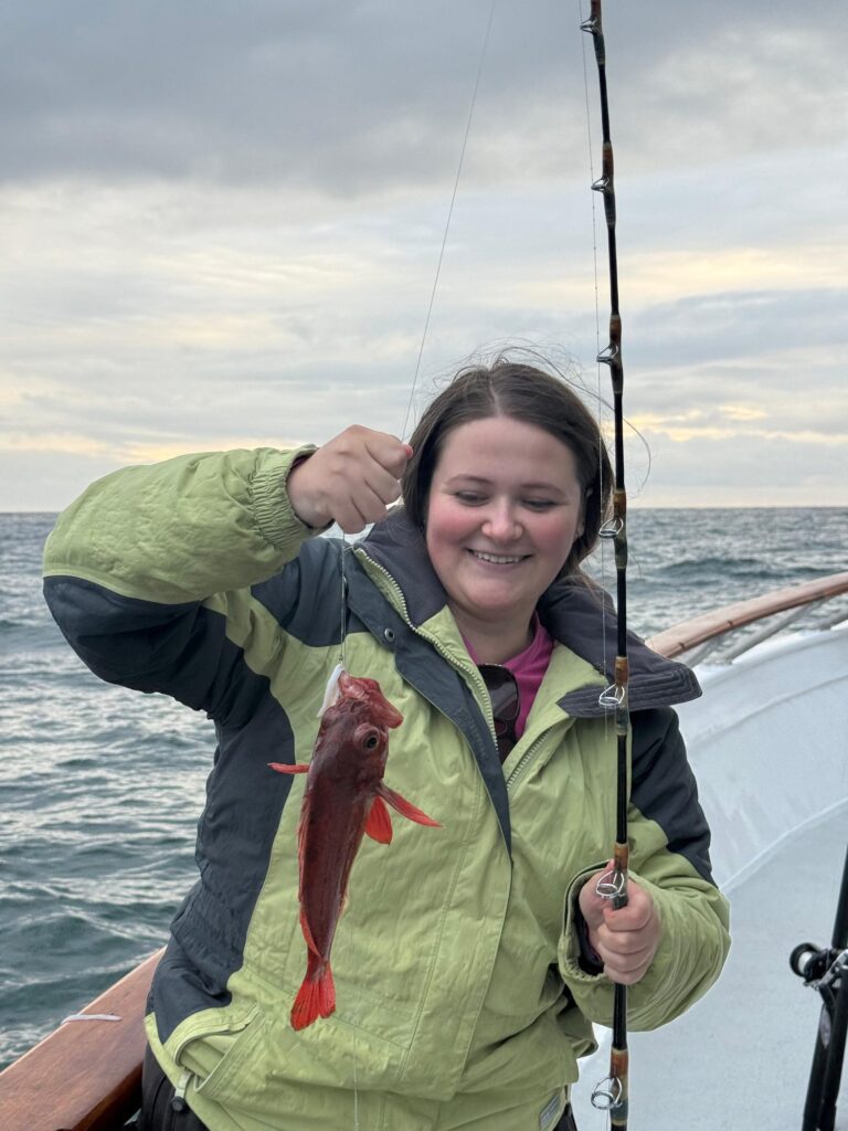 Student on a boat holding a caught fish — Black Tech Link BIPOC Coastal Research Program (BCRP)